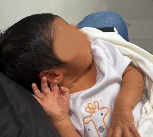 A wonderful little newborn baby with their hand raised.