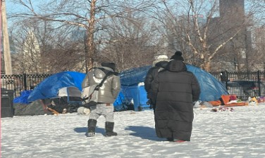 Migrants walking across the snow to tents with tarps o